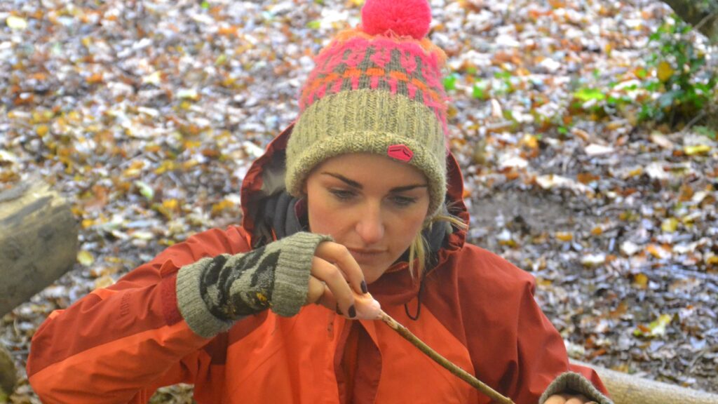 Lady with bobble hat toasting a marshmallow