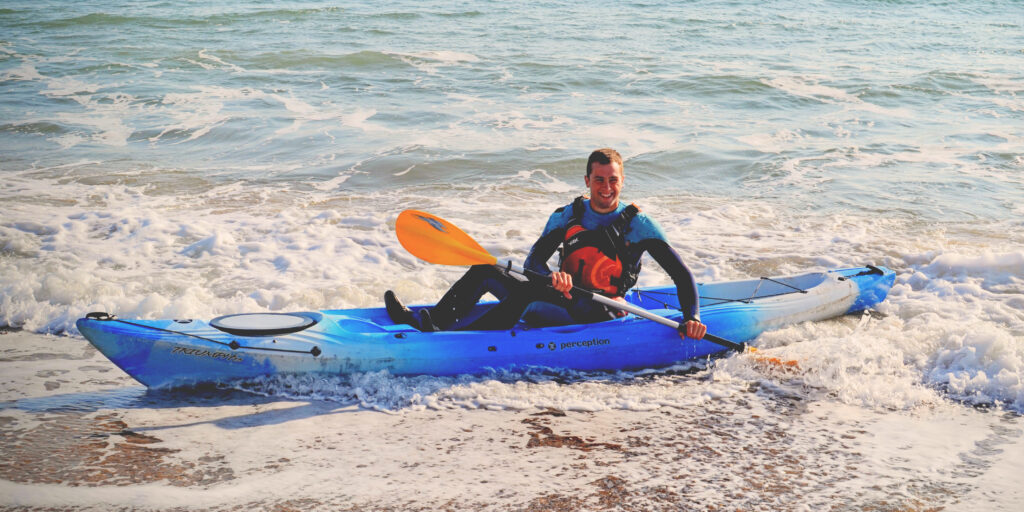 Trainee Instructor Course Member kayaking and paddling in the shallow water of the beach