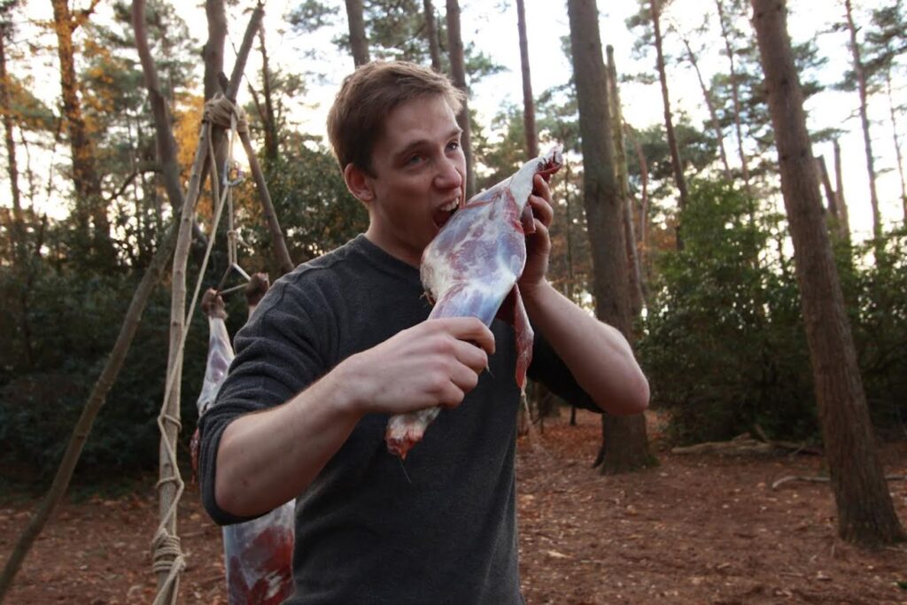 Man pretending to munch on raw deer leg on Accelerated Instructor Training Course