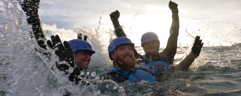 Three men coasteering at dusk near swanage, dorset