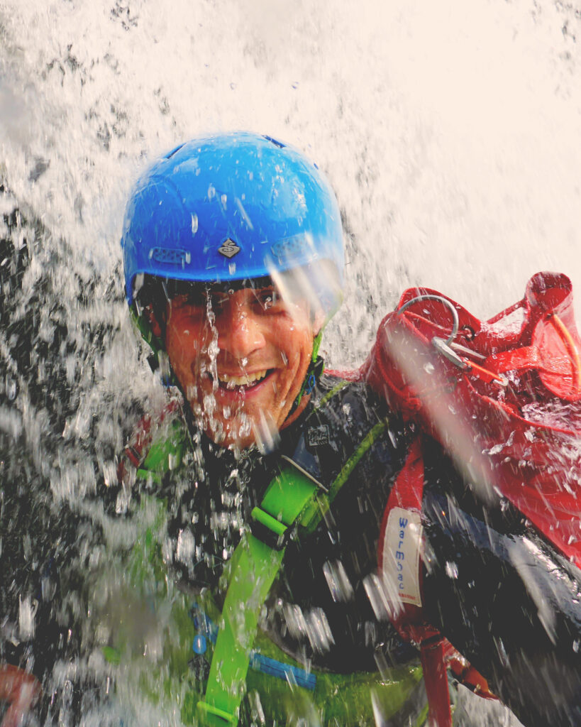 Man standing under waterfall whilst Coasteering