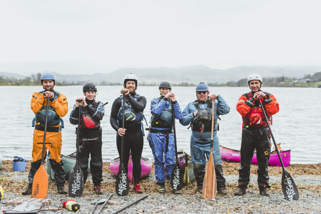 Four people standing near kayaks on the trainee instructor course