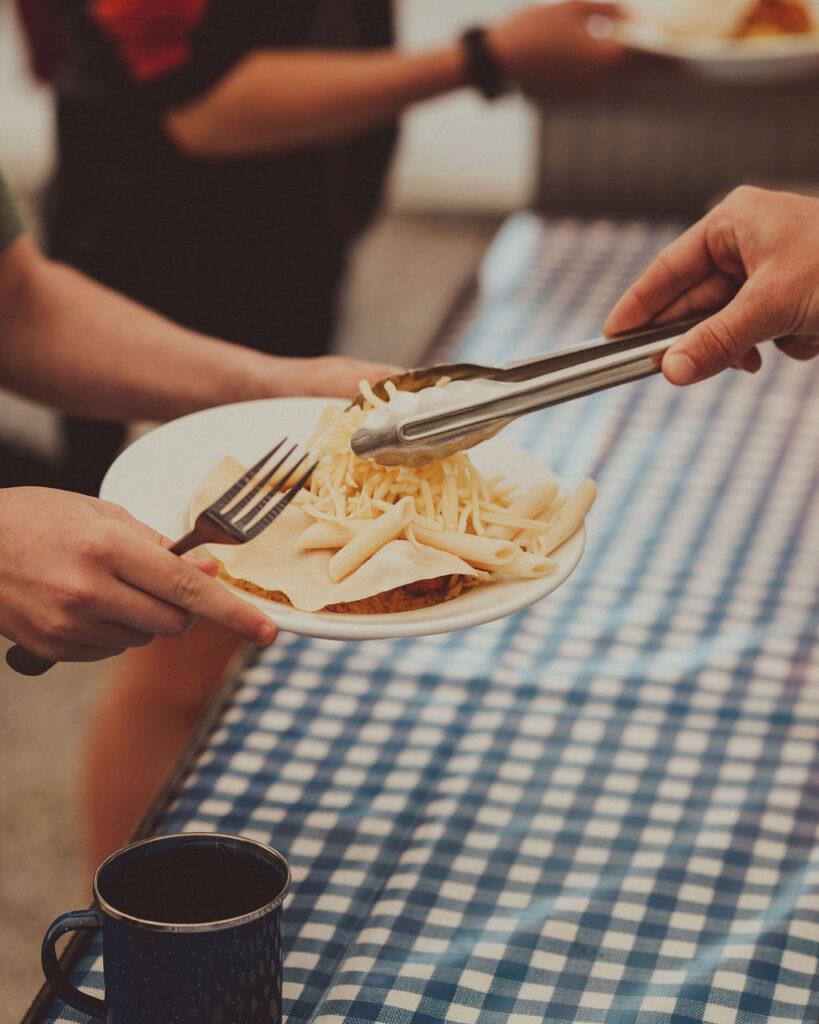 someone putting cheese on a clients plate 